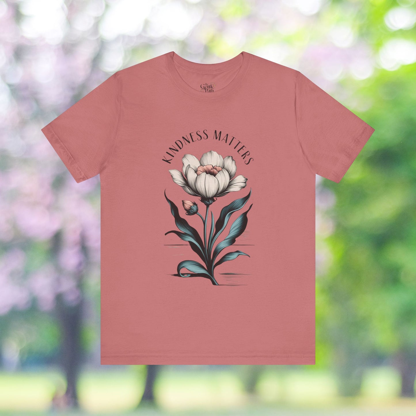 Salmon t-shirt with a Kindness Matters floral graphic.