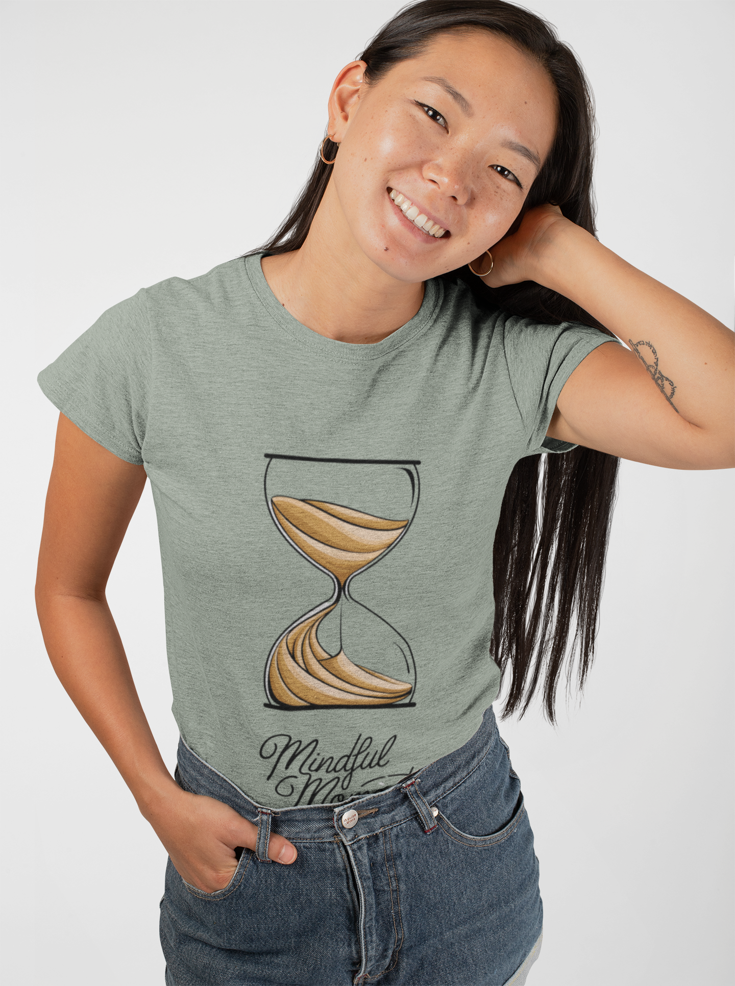 Woman wearing light green Mindful Moments T-shirt with hourglass graphic.