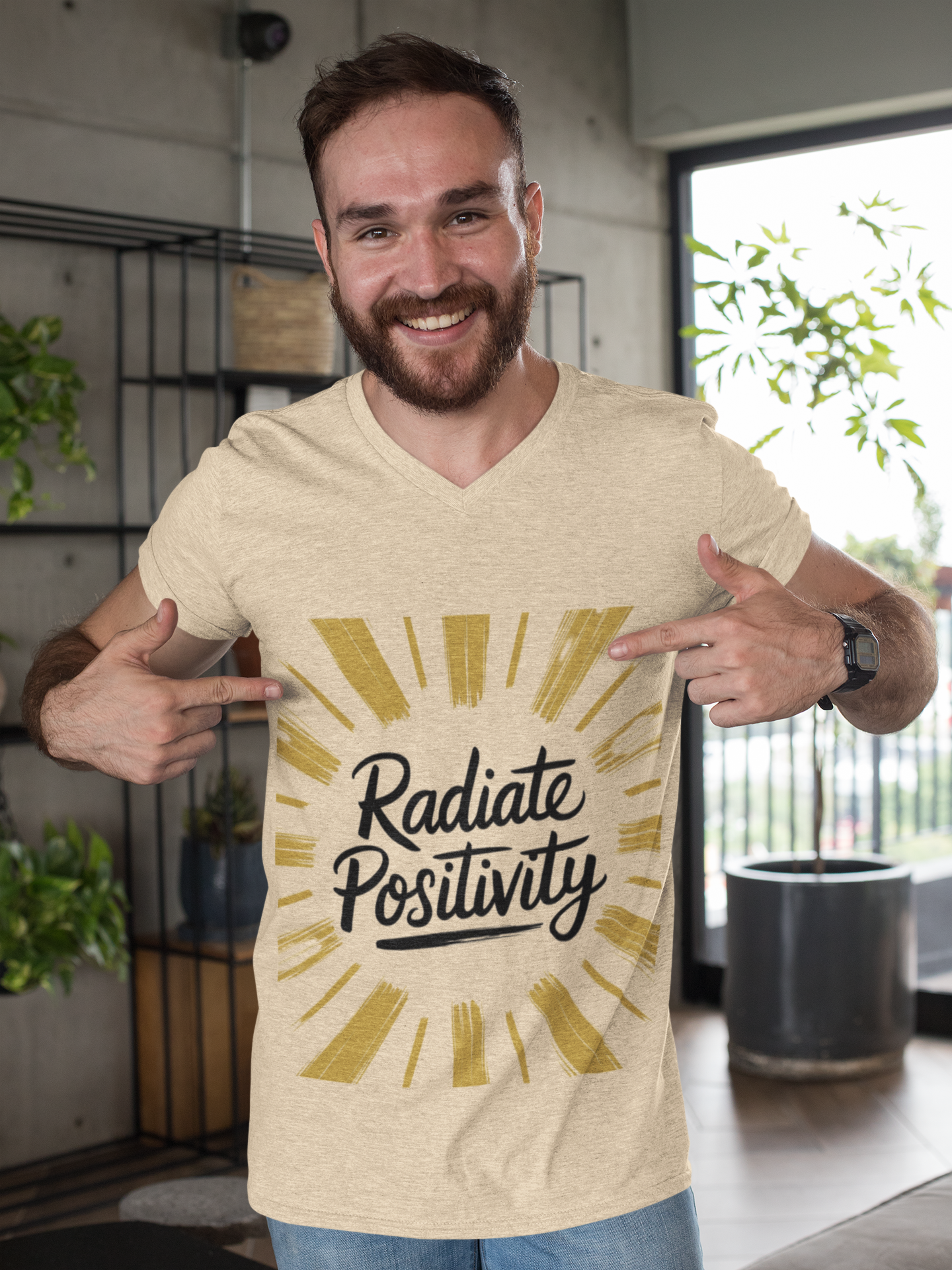 Man points to Radiate Positivity graphic on beige T-shirt.