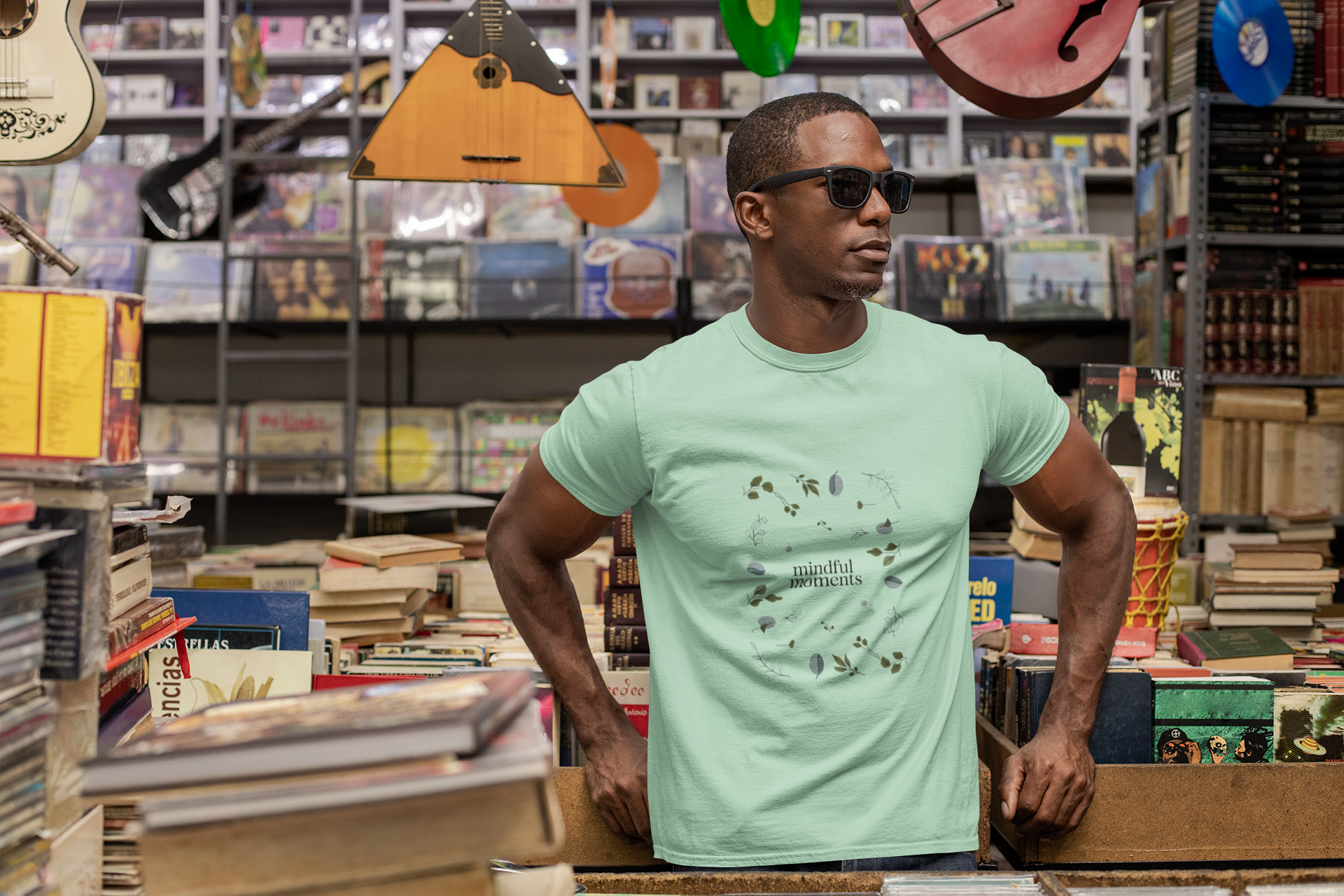 Man wears light green Mindful Moments t-shirt with botanical design.