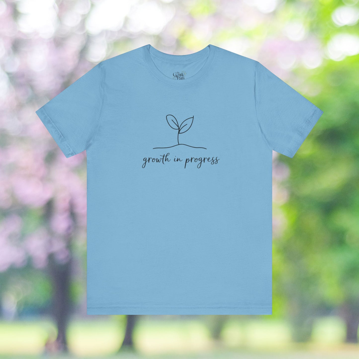 Light blue tee with growth in progress minimalist plant design.