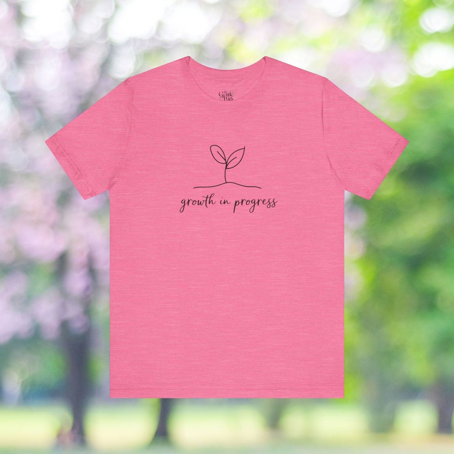 Pink tee with 'growth in progress' design, minimalist plant graphic.